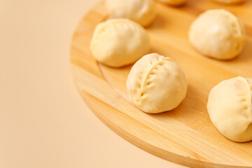 Close-up traditional Central Asian cuisine manty with meat on wooden board, frozen semi-finished products, copy space.