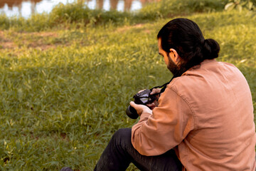 Long-haired, bearded Latino photographer, enjoying and documenting his journey. World photography day. Holidays and travel.