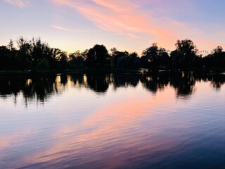 purple sky reflection on the lake surface, trees silhouettes reflection, twilights lake in the park