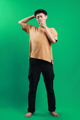 Full length of Tired Asian guy standing and yawning isolated on green background