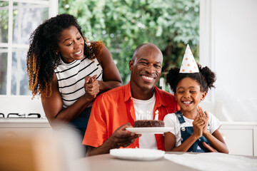 Family celebrating young girl's birthday with cake