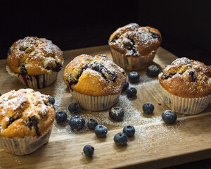 Homemade Blueberry Muffins on a wood tablet with berries and sugar