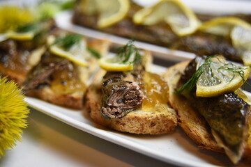 
Fried lampreys on a sandwich on a white plate, decorated with lemon