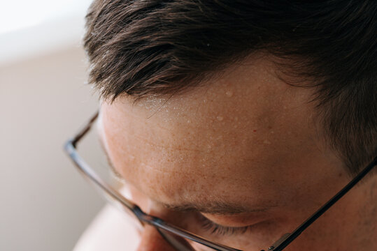 Close-up of Man Forehead with Sweat and Glasses. It hot summer day, stuffy room.