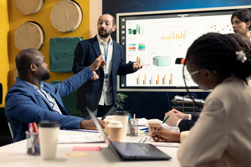 Business affiliates meeting to share insight and exchange opinions about infographics and statistics extracted from online research. Team collaborating on organizational development plan.