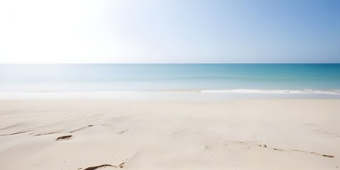 An isolated sandy beach background with gentle waves lapping at the shore, with copy space under a clear blue sky