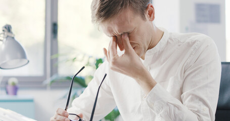 Stressed businessman touching his eyes