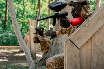 Obraz premium in the wild near tree structures player in a pintball uniform holds a pistol with a balloon team game camouflage clothing communication using hands