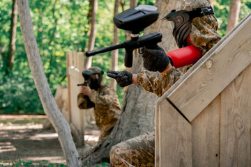 Obraz premium in the wild near tree structures player in a pintball uniform holds a pistol with a balloon team game camouflage clothing communication using hands