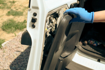 Repair of plastic car upholstery. A woman's hand changes a plastic clip on a car door panel.