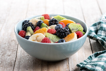 Fruit salad in a blue bowl on wooden table