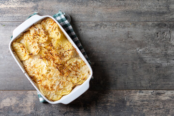Potato gratin baked with cream and cheese on wooden table. Top view. Copy space