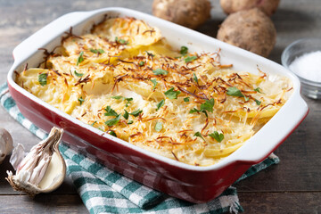 Potato gratin baked with cream and cheese on wooden table. 