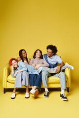 A diverse group of friends, including a nonbinary individual, casually seated on a bright yellow...