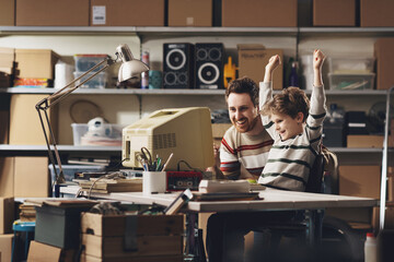 Happy father and son using together a vintage computer