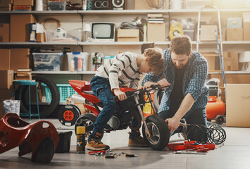 Father checking the son's motorbike in the garage