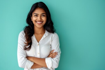 Obraz premium Portrait of a merry indian woman in her 30s with arms crossed isolated in soft teal background