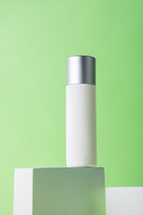 Plastic white tube for cream or lotion. Skin care or sunscreen cosmetic with stylish props on green background.