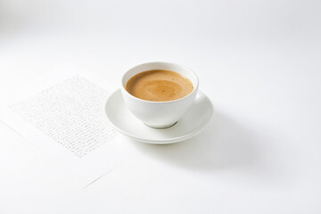 Close-up of a cup of coffee on a white background with a piece of paper with writing on it