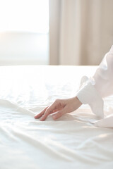 Hand on a soft duvet. Woman touching bed sheets, closeup. Young woman intimacy on bed. Soft, gentle, tender cozy morning concept