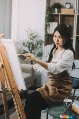 Obraz premium Pretty talented female painter painting on easel, making colorful sketches, creating marine landscape. Beautiful female artist painting with watercolor paints. Creativity and imagination concept