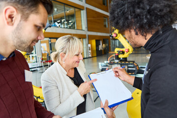 Team of engineers discussing robotics development and programming in industrial setting