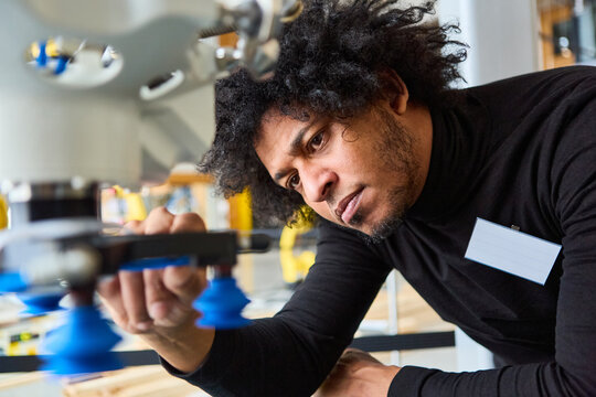 Engineer programming robotic gripper arm for industrial application and process automation