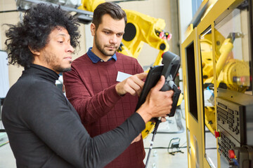 Engineers programming industrial robot arm in a modern manufacturing facility