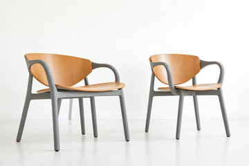 Obraz premium Two modern chairs with wooden seats and grey legs on a white background