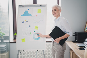 Photo of smiling good mood mature lady specialist formalwear analyzing graphs indoors workplace...