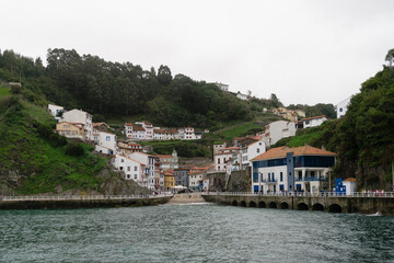 Fototapeta premium Picturesque view of Cudillero, a charming coastal town with colorful houses located on a lush hillside and overlooking the serene waters of the bay. Asturias - Spain