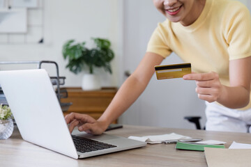 Woman Using Credit Card for Online Shopping on Laptop in Modern Home Office Setting