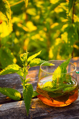Nettle tea on a rough wooden background among nettles.
