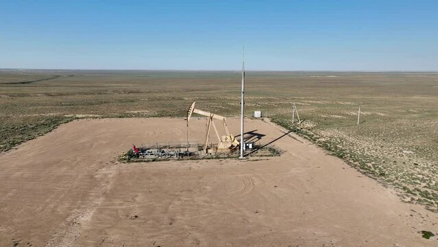 Warking oil well in the steppe on a sunny summer day. 