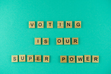 Words voting is our superpower. The phrase is laid out in wooden letters. Top view. Blue background.