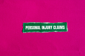 Personal injury claims message written on ripped green paper piece with pink background. Conceptual personal injury claims symbol. Copy space.