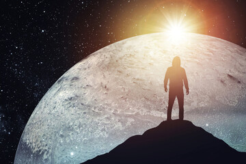Silhouette of a man standing on the top of a mountain against the backdrop of the planet. Elements...