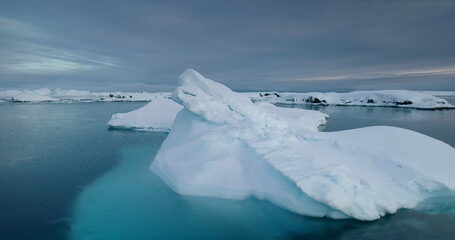 Glaciers melting in arctic icy lagoon, moody sky over floating snow covered icebergs. Calm water polar frozen winter landscape, natural beauty of cold environment. Antarctica wildlife panoramic shot