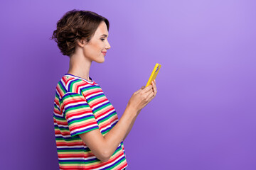 Profile portrait of pretty positive lady use smart phone texting empty space isolated on purple color background