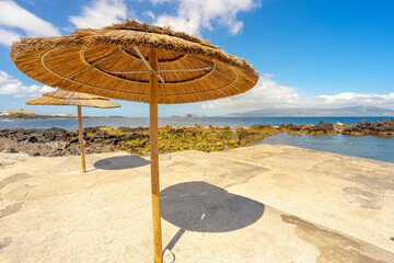 Barca bathing area with natural pools and straw umbrellas. Pico Island in the Azores archipelago.