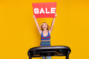 Photo of funny crazy screaming woman in casual garment announce sale for sports equipment running racetrack isolated on yellow color background