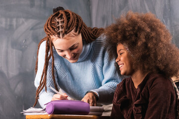 Supportive teacher-student relationships. Young woman tutor comforting upset African girl student while preparing her for test in school. Private tutoring concept