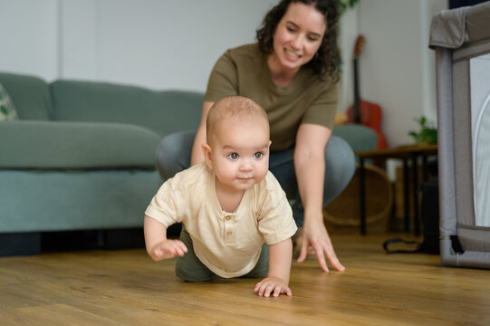 Caucasian mother teaches baby to crawl at home