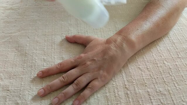 Primer plano de una mano de mujer colocando una crema humectante en su mano y brazo despu&eacute;s de un d&iacute;a de  sol