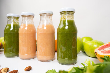 Different vegetable and fruit smoothies in glass bottles on white background