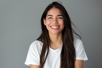 Fototapeta premium Portrait of a young latino femal smiling with long hair and white t shirt.