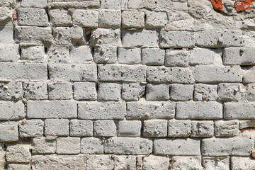Texture of an old damaged brick wall covered with thick layer of plaster as a background