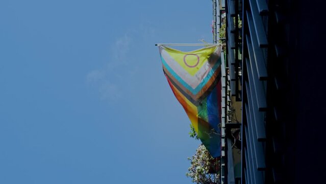 Bandera LGBTQIA+ ondeando al viento en un balc&oacute;n de un edificio de un barrio de Madrid en Espa&ntilde;a.
