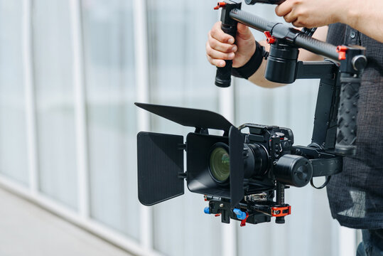 videographer working outdoors in park with video camera set on steadycam, cameraman at work