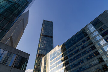 A low-angle view of modern skyscrapers in Moscow, Russia, showcasing their sleek glass facades against a clear blue sky.